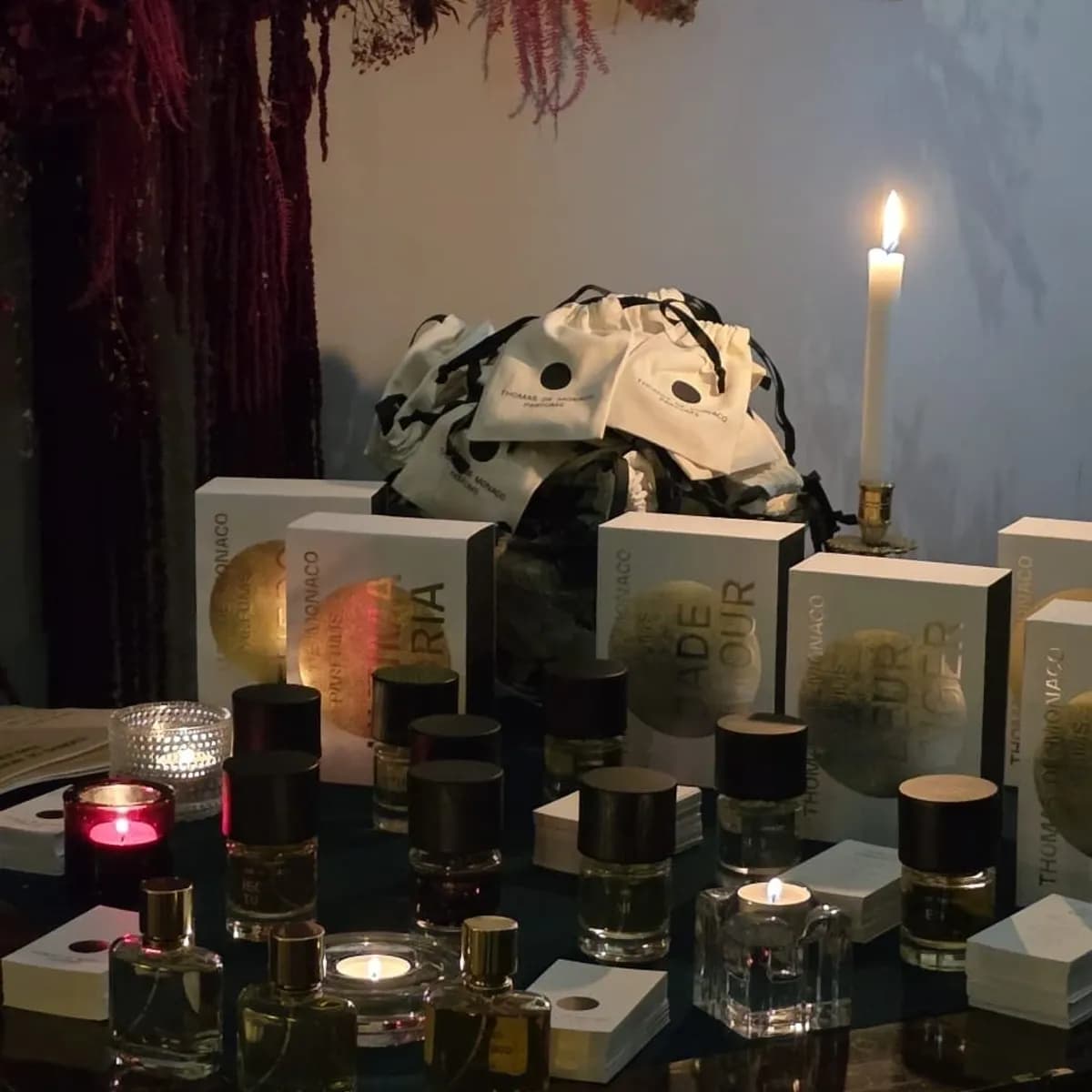 Niche perfume bottles and boxes displayed by candlelight at a club event