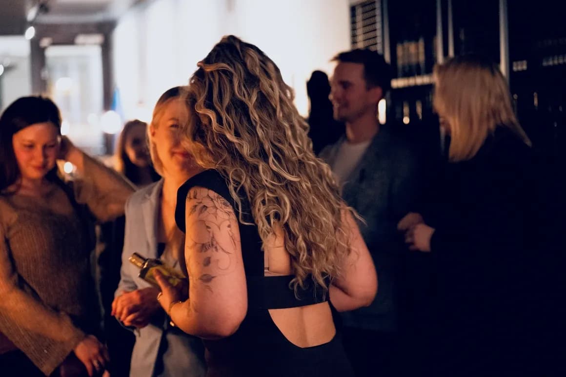 Members talking and smelling perfume at a candlelit club evening